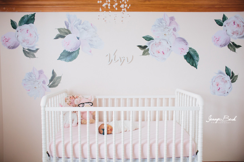 westerville ohio newborn photographer - newborn girl swaddled in crib with pink sheet and large flowers on the wall behind
