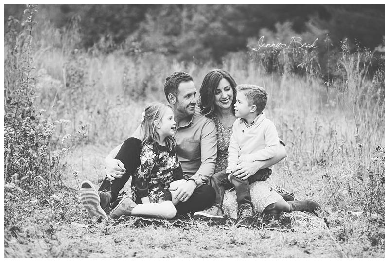 black and white photograph of family sitting in new albany ohio nature park smiling and enjoying each other