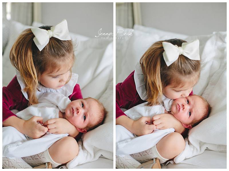 big sister kissing newborn sister's cheek