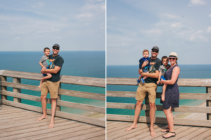 young family smiling on observation deck with bright blue lake michigan water behind - on the sleeping bear dunes scenic drive.