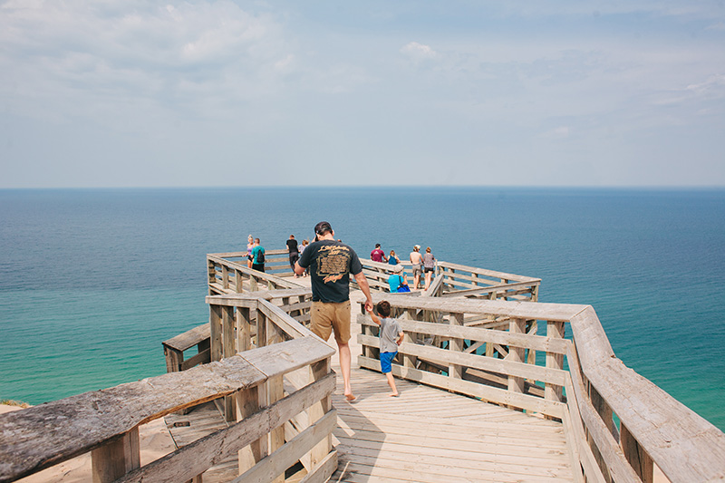 dad and young boy walking on the observation deck over looking lake michigan