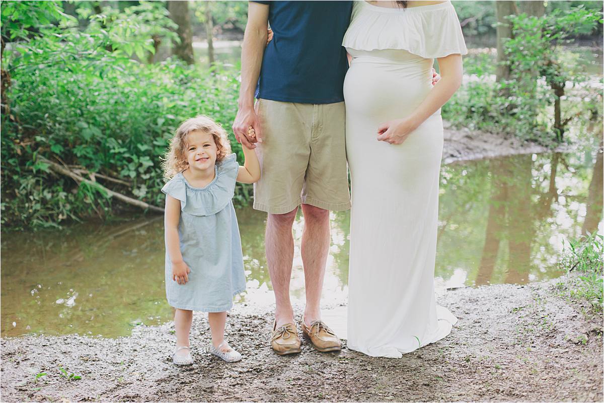 new albany ohio maternity photographer - expecting mom in white dress standing with husband and 2 year old daughter, photo from neck down