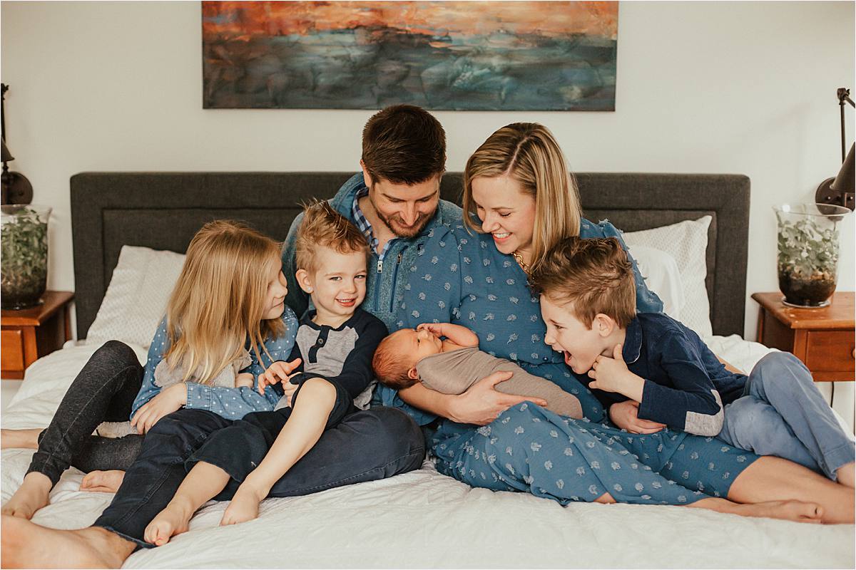 westerville ohio minimal newborn photography - family sitting on bed looking at new baby