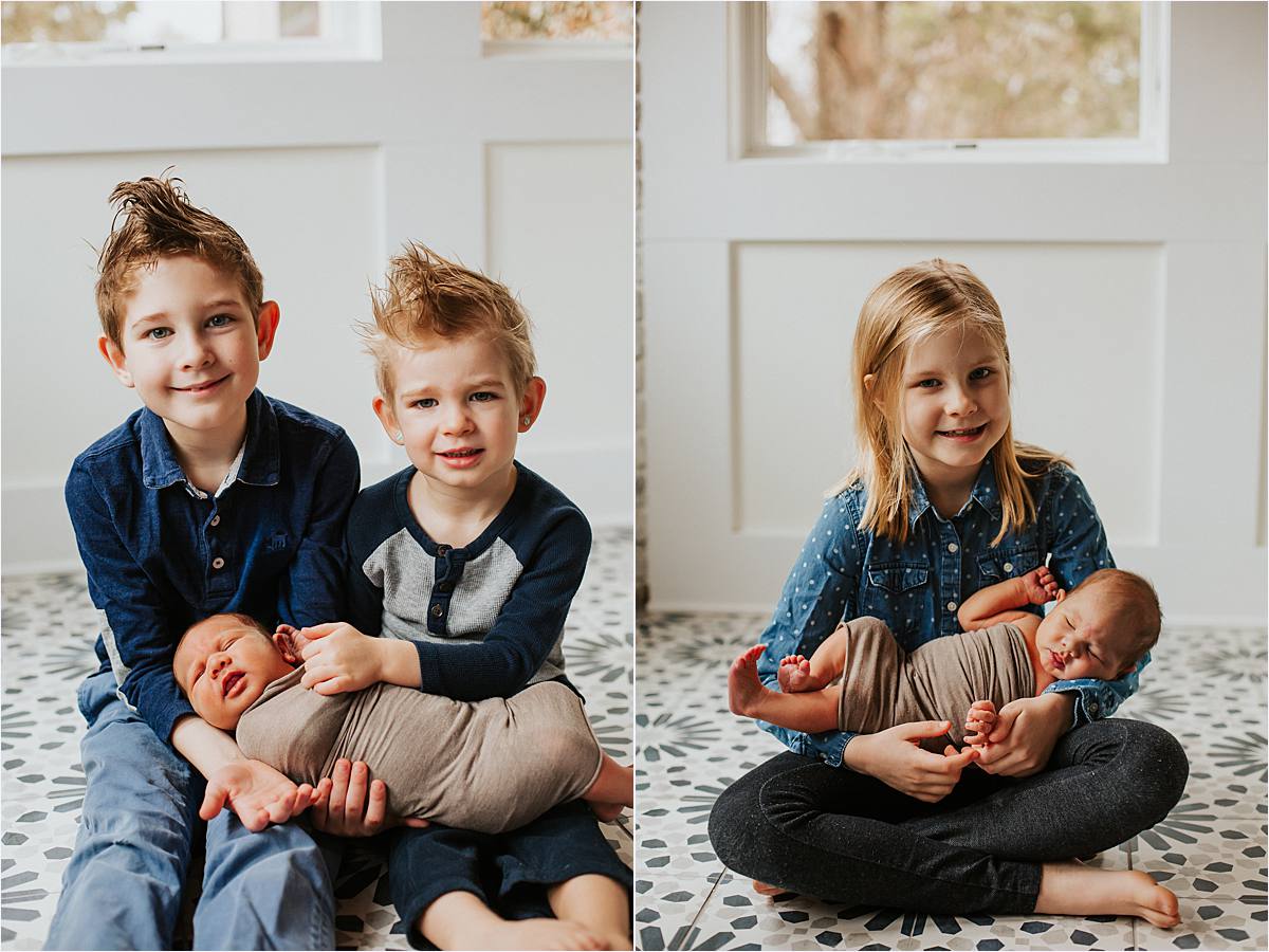 westerville ohio minimal newborn photography - older siblings holding newborn baby sitting on floor